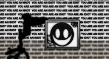 a picture of a smiley face with the words " you are an idiot " behind it