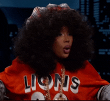 a woman wearing a red lions jersey and a plaid hat