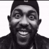 a black and white photo of a man with a beard smiling .