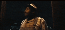 a man wearing overalls and a hat is screaming with his arms outstretched