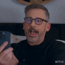 a man with glasses and a beard says " hey "