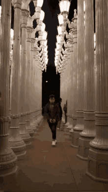 a man is running through a hallway of columns and lights