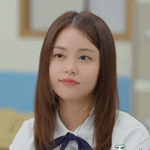 a girl wearing a white shirt with a blue bow and the letter z on the sleeve