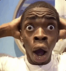 a man is making a funny face with his hands on his head and his mouth open .