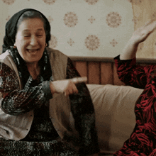 two women are sitting on a couch and one is pointing at the other