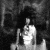 a black and white photo of a woman in a white dress with a skull in the background .