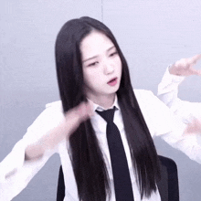 a woman with long black hair wearing a white shirt and black tie