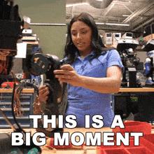 a woman holding a camera with the words this is a big moment written below her