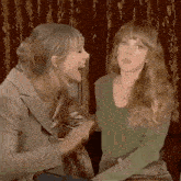 two women are sitting next to each other in a room and laughing .