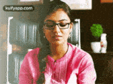 a woman wearing glasses is sitting in a chair in a room .