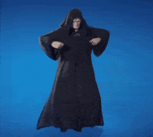 a man in a black robe with a hood is standing on a blue surface .