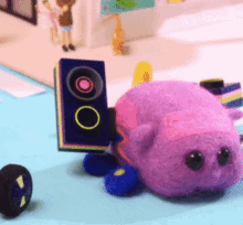 a purple stuffed animal is sitting on a table next to a speaker