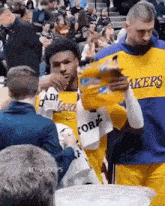 a man in a lakers jersey is holding a bottle of water