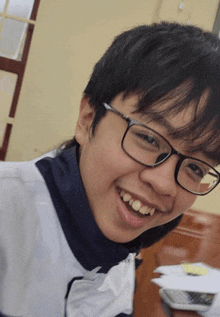 a young man wearing glasses and a white shirt smiles for the camera
