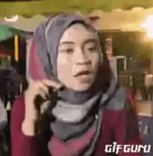 a woman in a hijab is talking on a cell phone .