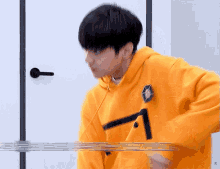 a young man in a yellow hoodie is standing in front of a white door .