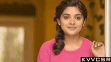 a woman in a pink shirt is standing in front of a door with the letters kvvcsr above her