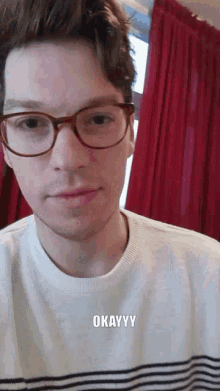 a young man wearing glasses and a striped shirt says okayyy