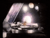 a person is playing a record on a turntable with a purple light behind them .