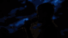 a man is singing into a microphone in the dark