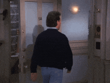 a man in a black sweater is walking towards a door that says 5a on it
