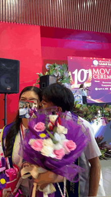 a man kisses a woman on the cheek in front of a screen that says 10