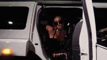 a woman wearing sunglasses is getting out of a car