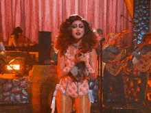 a woman sings into a microphone while a man plays a guitar