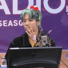 a man with green hair is sitting in front of a monitor with the word season on it