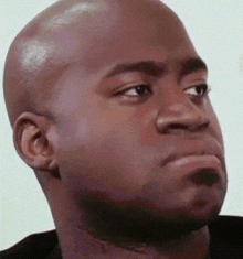a bald man with a beard is making a funny face while looking at the camera .