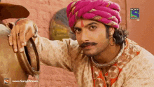 a man with a pink turban and a mustache is on a sony television show