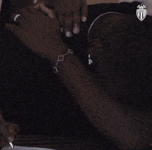 a man wearing a bracelet and a ring is crying while sitting down .