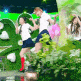 a group of people are dancing in front of a green wall