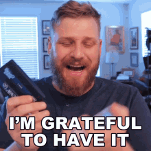 a man with a beard is holding a box that says ' i 'm grateful to have it '