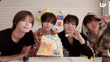 a group of young men are sitting around a table with a cake in front of them