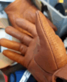 a close up of a person 's hands wearing a pair of brown leather gloves