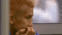 a close up of a person 's face with their hand on their chin