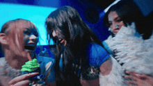a woman holding a cupcake with green frosting and a straw in her mouth