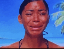 a woman in a bikini is crying while standing on a beach .