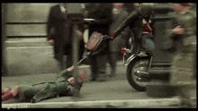 a man on a motorcycle is pulling another man on the ground