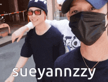 two men wearing face masks and sunglasses are standing next to each other with the name sueyannzzy on the bottom