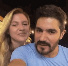 a man with a beard and a woman in a blue shirt are posing for a selfie .