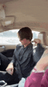 a man is sitting in the back seat of a car with his seat belt on .