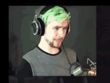 a man with green hair is wearing headphones .