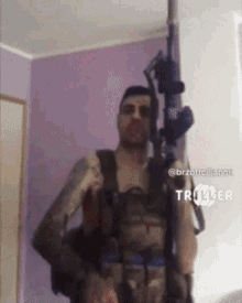 a man is holding a gun in front of a purple wall and the words triller on the bottom right