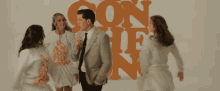 a man and two women are dancing in front of a wall that says ' con hi '