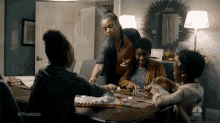 a group of people are sitting around a table with a nbc logo on the bottom right