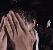 a close up of a person covering their face with their hands in the dark .