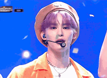 a boy with purple hair wearing a yellow hat and a microphone