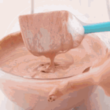 a person is using a spatula to stir a bowl of chocolate frosting